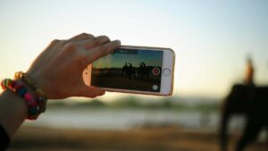 A person holding a smartphone, is filming a group of people.